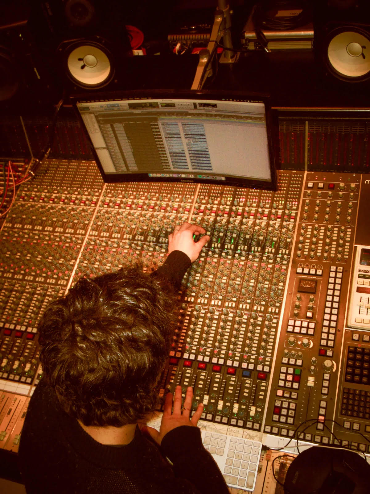 Engineer at a large mixing console in a dim studio